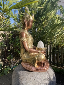 Seitenansicht der goldenen Buddhafigur mit Sockel