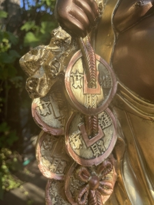 Goldene Buddhafigur mit Muenzen als Detail