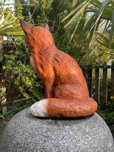 Sitzender Deko Fuchs als Gartenfigur in der Vorderansicht.