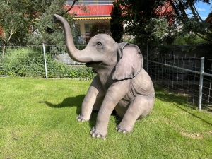 Dekofigur Elefant sitzend in einer schraeg vorderen Ansicht.