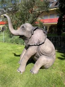 Gartenfigur Elefant sitzend mit natuerlicher Gesamtansicht.