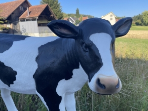 Fressende schwarz-weisse Kuhfigur mit gesenktem Kopf