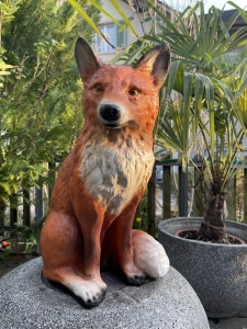 Fuchs Gartenfigur sitzend in einer schraeg vorderen Ansicht.
