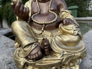 Schraegansicht der gold-braunen Gluecksbuddha Gartenfigur