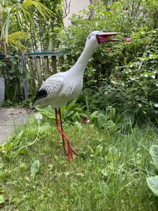 Stehender Deko Storch schraeg von vorne fotografiert.