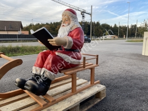 Grosser Weihnachtsmann auf Schlitten liest im Buch 