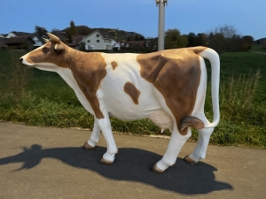 braun-weisse kuhfigur lebensgross in der seitlichen gartenansicht
