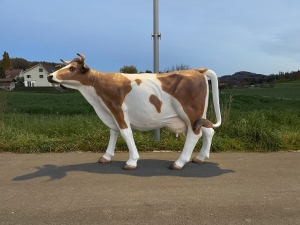 lebensgrosse braun-weisse kuhfigur als gartendeko in der gesamtansicht