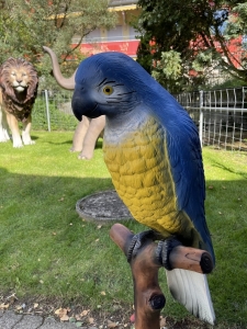 Kopfdetail der Papageienfigur mit blau-gelbem Gefieder