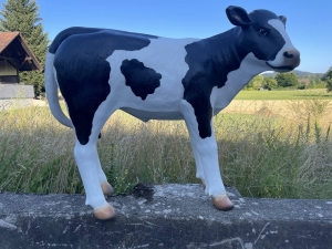 Schwarz-weisse Kuhfigur mit gesenktem Kopf von der Seite