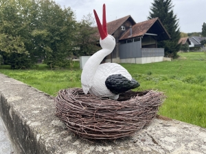 Grosses Storchennest mit einem sitzenden Storch als Gartenfigur.