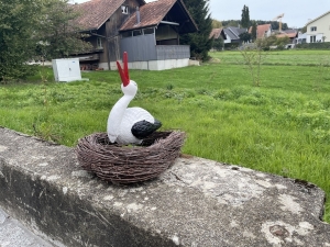 Storchennest mit sitzendem Storch auf einer Gartenmauer.