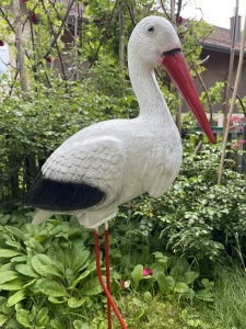 Storchfigur stehend mit Kopf und langem rotem Schnabel.