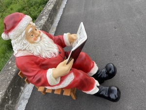 Detailansicht des Weihnachtsmanns mit Buch auf Holzschlitten.
