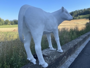 Weisse Gartenfigur Kuh von hinten seitlich betrachtet.