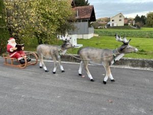 Zwei Rentiere und Weihnachtsmann mit Schlitten in weiter Ansicht.